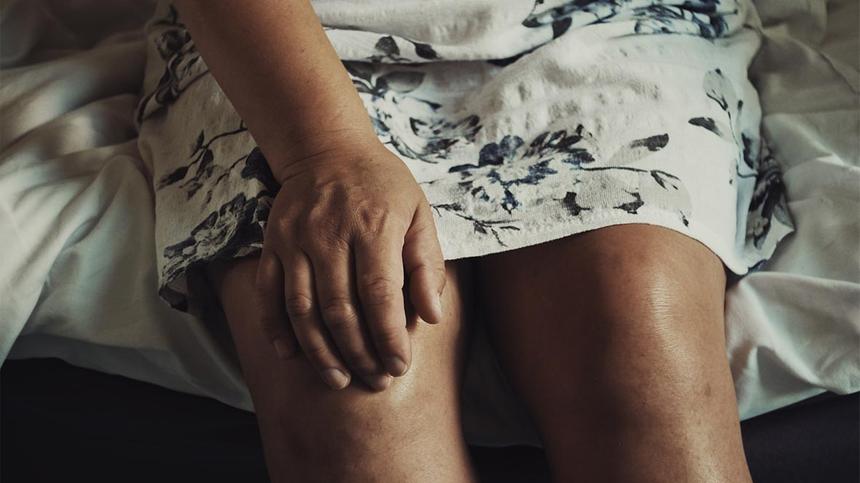 Gelenkschmerzen Wechseljahre - Frau fasst sich ans Knie