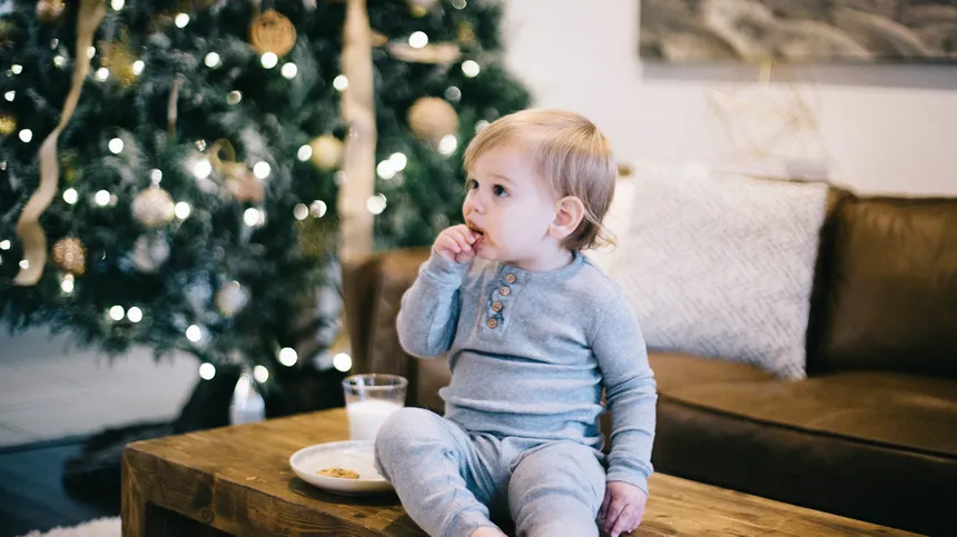 Kind sitzt vor einem Weihnachtsbaum