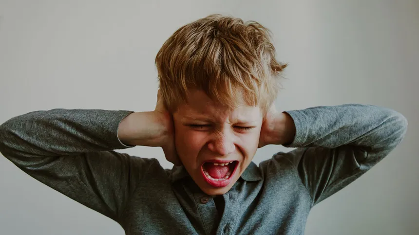 Wahrnehmungsstörung: Kind hält sich die Ohren zu und schreit