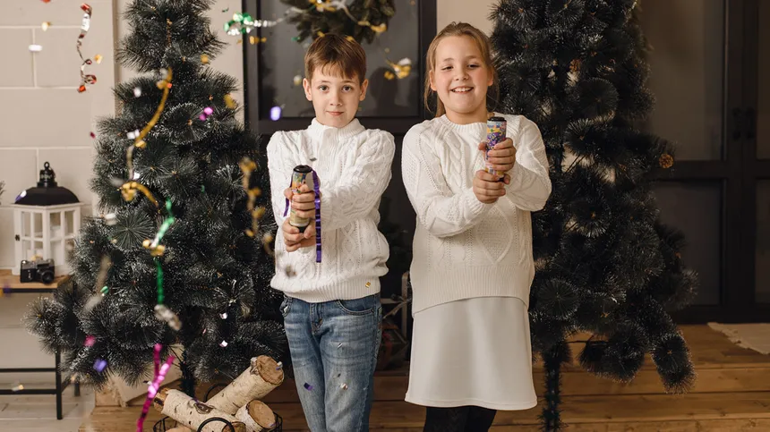 Zwei Kinder lassen je ein Knallbonbon an Silvester hochgehen