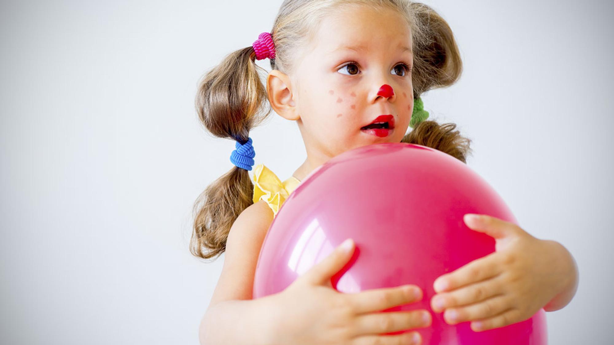 Verkleidetes Mädchen spielt Faschingsspiel mit Luftballon