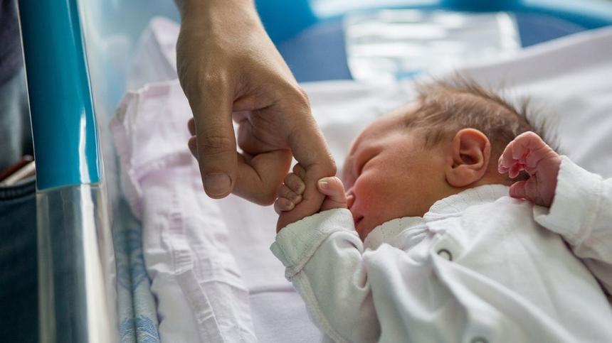 Neugeborenes hält Finger von Mama