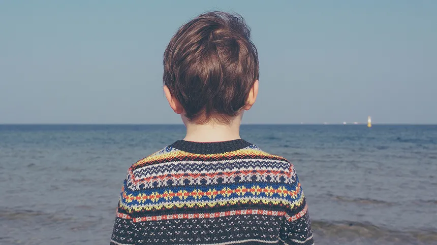 Junge mit Pullover starrt aufs Meer