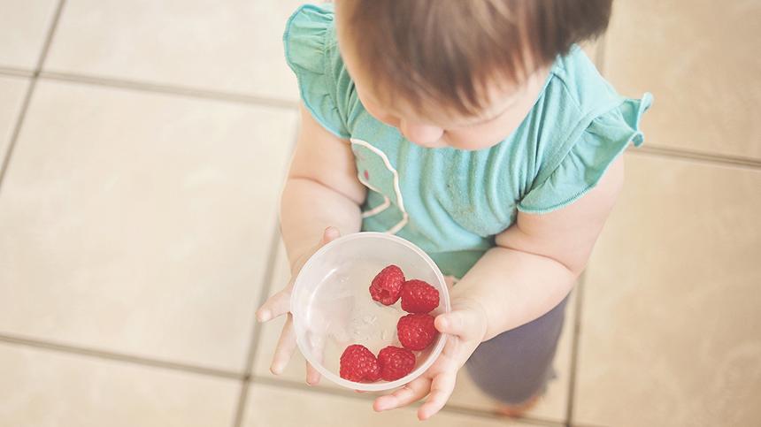 Kind hält eine Schüssel Erdbeeren in der Hand