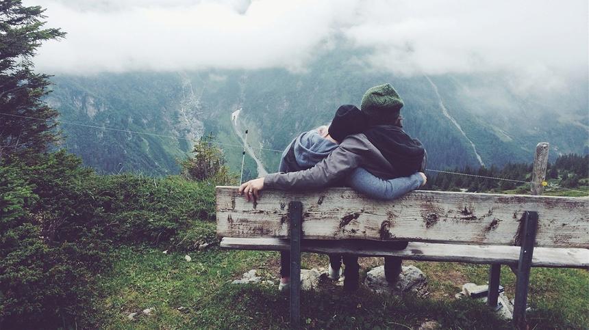 Ein Paar sitzt auf einer Bank in den Bergen