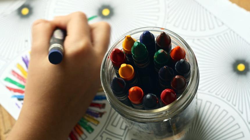 Ein Kind malt ein Bild mit Wachststiften