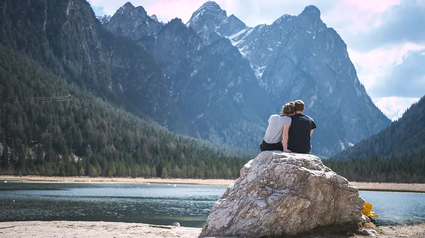 Ein Paar sitzt auf einem Fels in der Nähe eines Sees