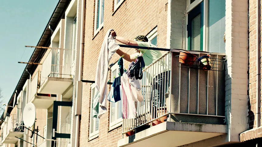 Frau hängt auf dem Balkon Wäsche auf