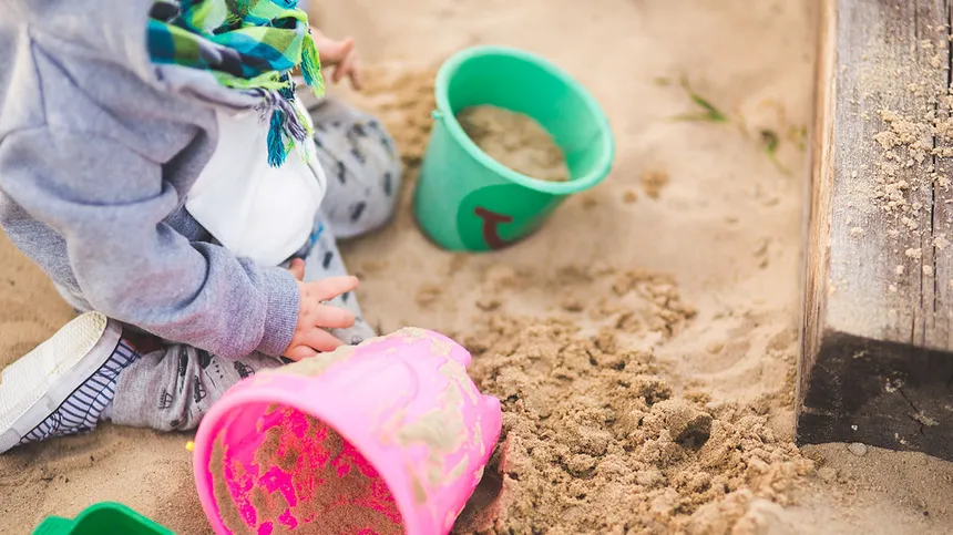 Kind spielt mit Förmchen im Sandkasten