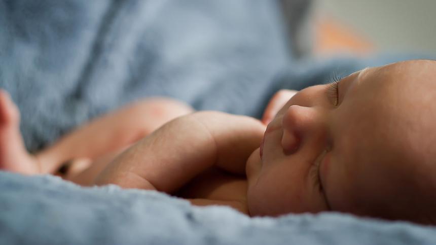 Ferber-Methode:Baby liegt schlafend in eine Decke gehüllt