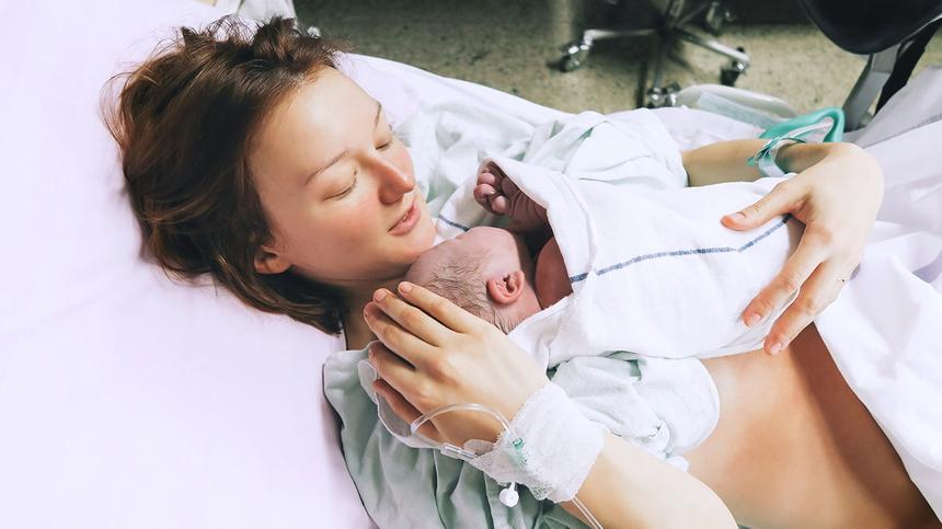 Frau mit Neugeborenem im Arm