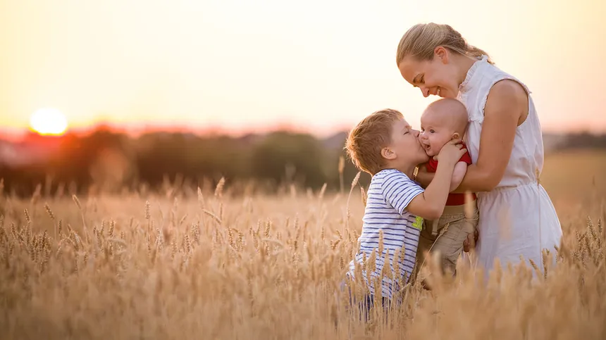 Mutter mit ihren zwei Kindern in einem Weizenfeld