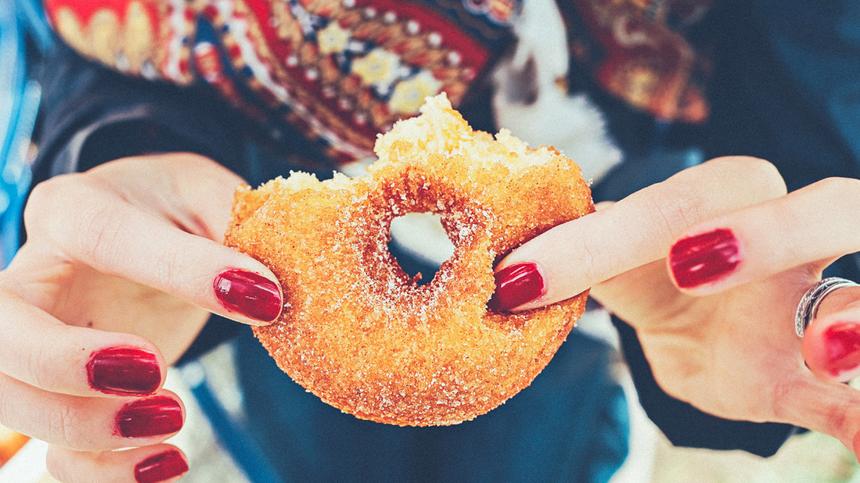 Zuckerkonsum, Frau hält Donut in der Hand