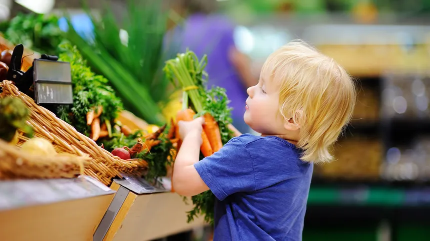 Kind im Supermarkt am Gemüseregal