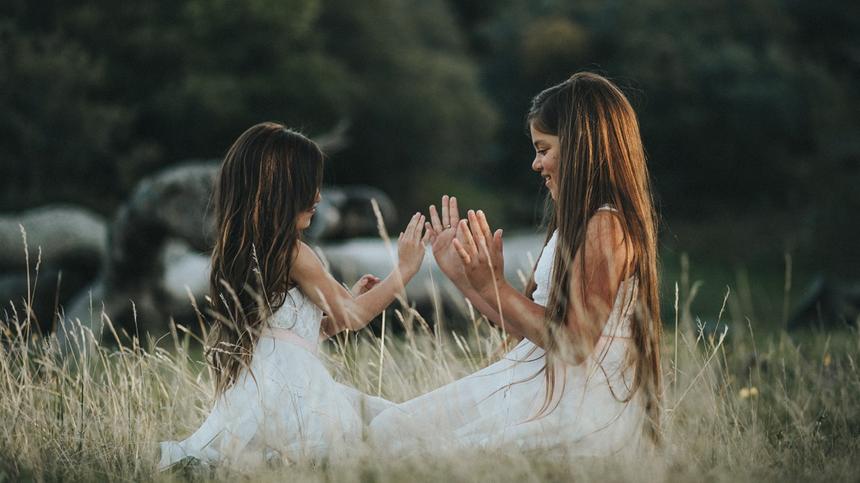 Zwei Schwestern sitzen im Gras und spielen