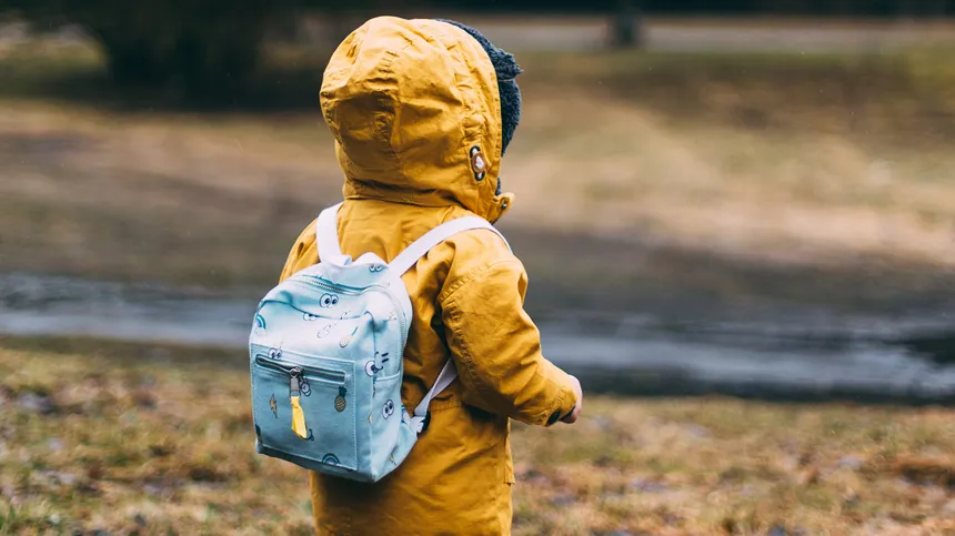 Kind geht mit Rucksack im Wald spazieren