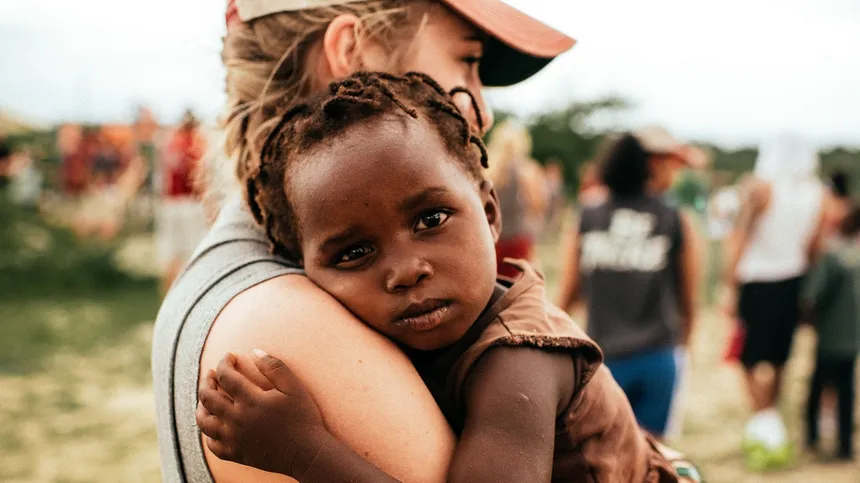Frau umarmt afrikanisches Kind