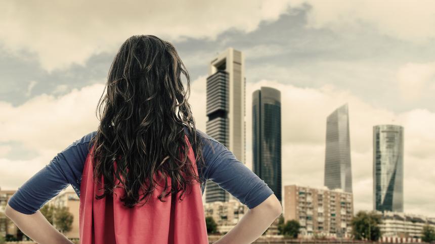 Frau mit Superheldenkostüm schaut auf eine Stadt