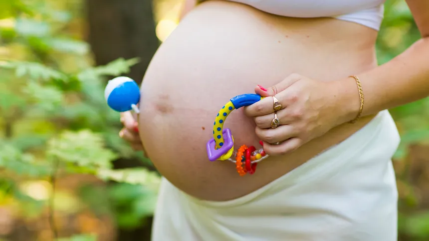 Eine Schwangere hält Kinderspielzeug in der Hand