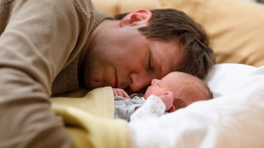 Vater schläft mit Baby auf einem Bett