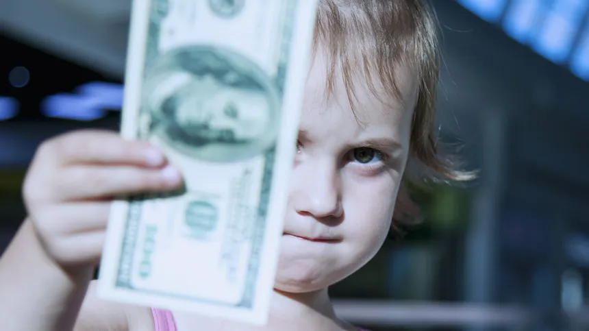 Ein kleines Kind hält einen Dollarschein in der Hand