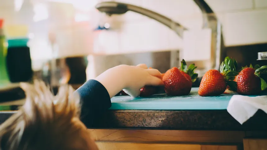 Ein Kind greift nach Erdbeeren