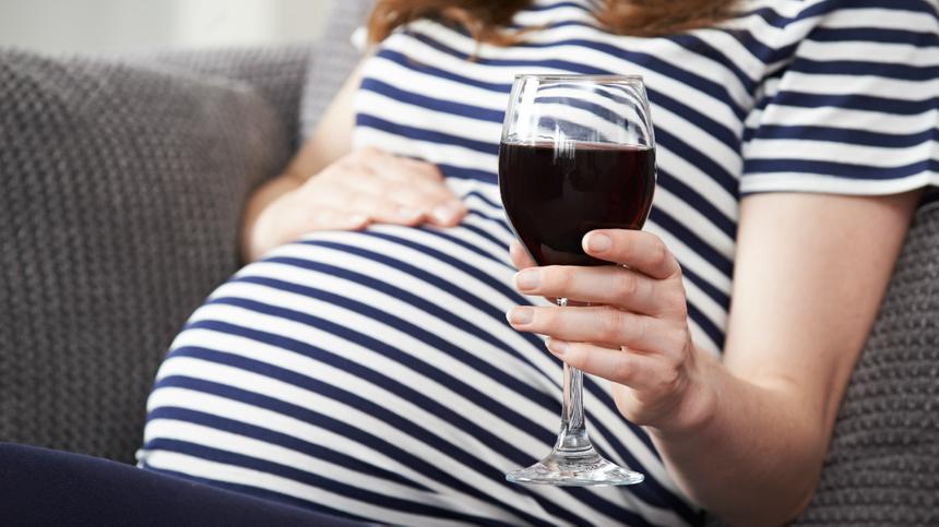 Eine Schwangere hält ein Glas Rotwein