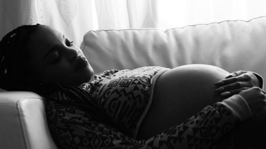 Frau hat Unterleibsschmerzen in der Schwangerschaft und liegt auf dem Sofa