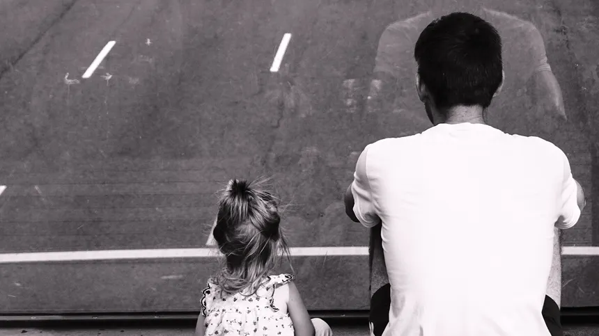 Vater und Tochter sitzen zusammen und schauen auf die Straße