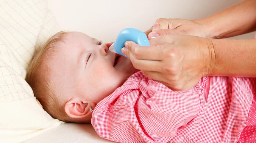 Baby mit Schnupfen benutzt einen Nasensauger