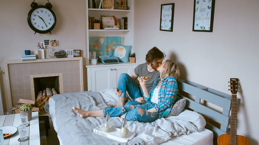 Mit dem Ovulationstest gelingt es vielleicht auch diesem Paar, das verliebt auf dem Bett sitzt und sich küsst, die fruchtbaren Tage und den Eisprung zu bestimmen.