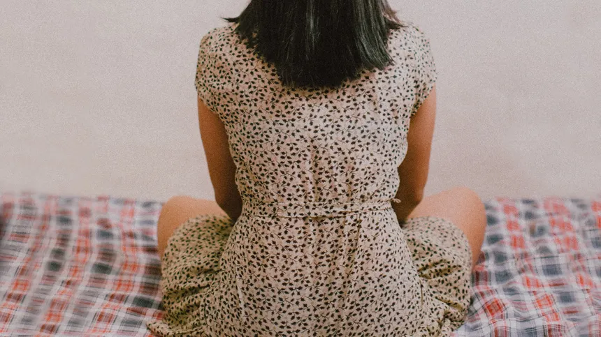 Rücken einer jungen Frau im gepunkteten Kleid