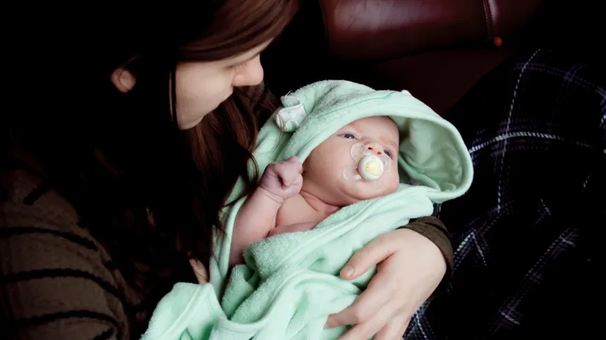 Ein frisch gebadetes Baby liegt im Arm seiner Mutter - so macht Babypflege Freude