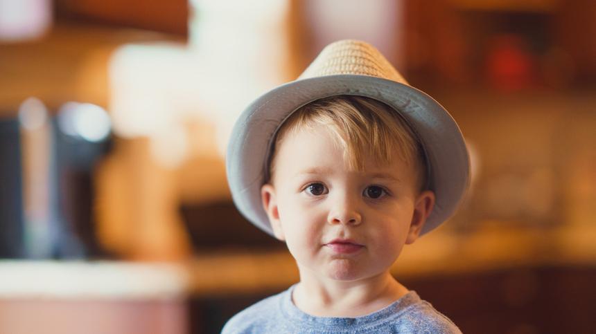 Ein kleiner Junge mit Hut schaut in die Kamera