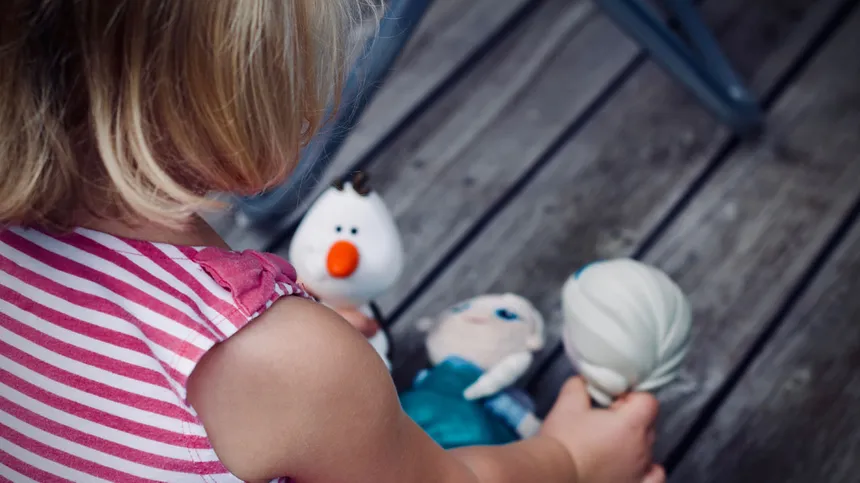 Blondes Kind spielt mit Puppen.