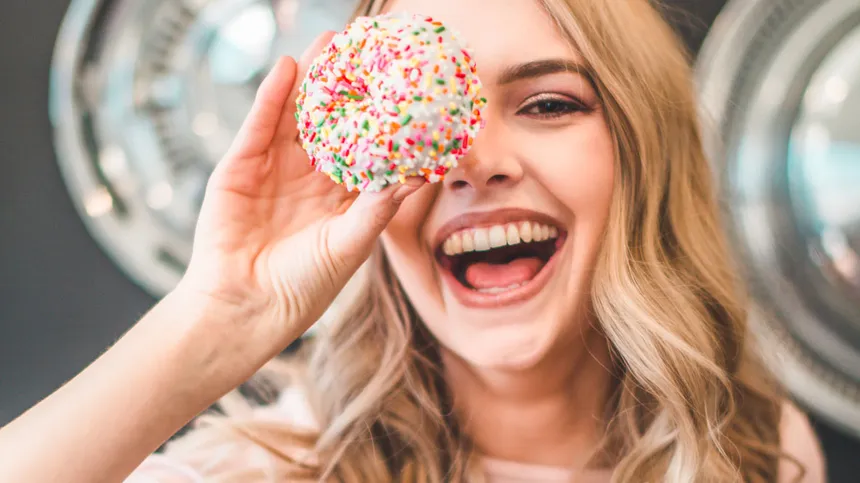 Blonde Frau lacht mit Donut