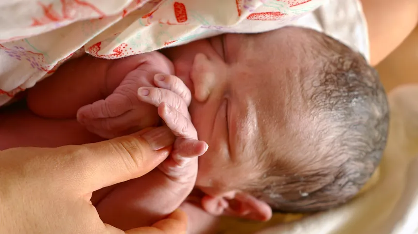 Neugeborenes Baby liegt nach einer Lotusgeburt im Arm seiner Mutter