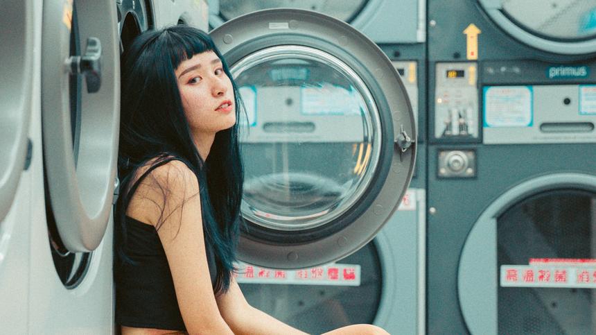 Frau sitzt vor einer Waschmaschine