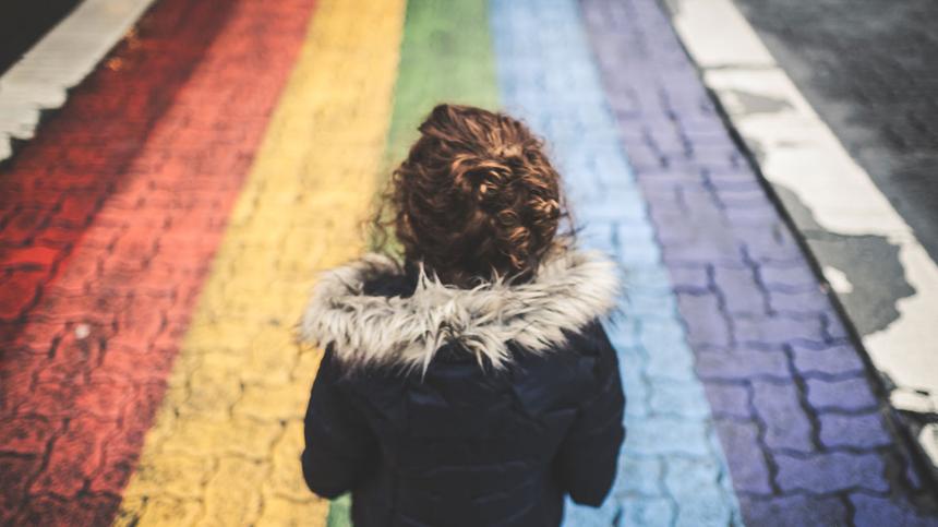 Kind geht auf einer Straße mit einem Regenbogen