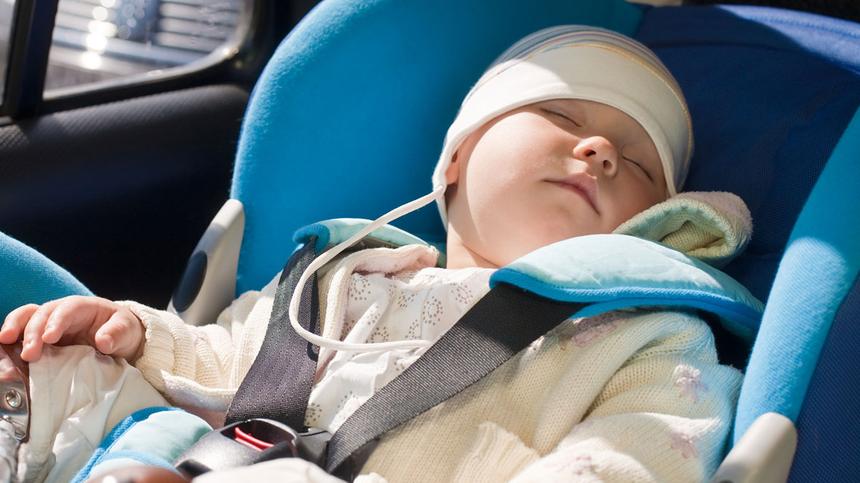 Kind schläft in Kindersitz im Auto