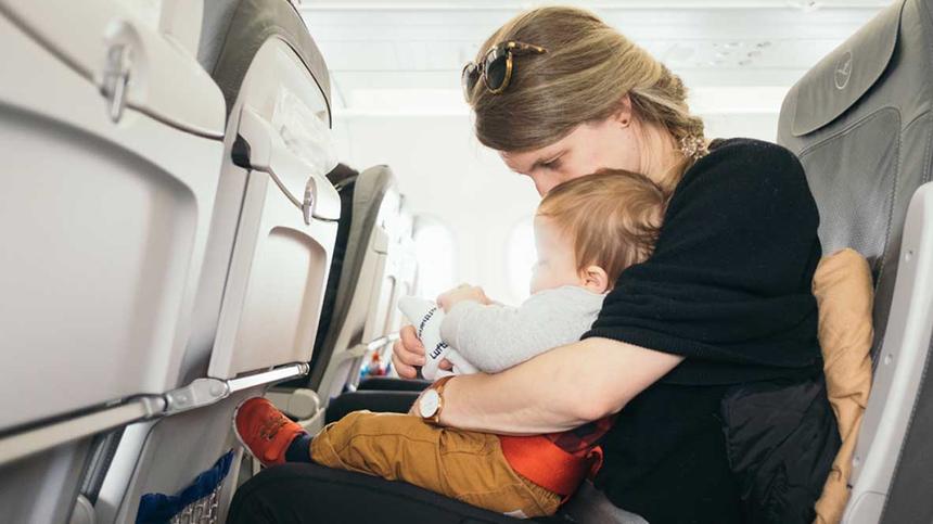 Frau sitzt mit ihrem Baby im Flugzeug