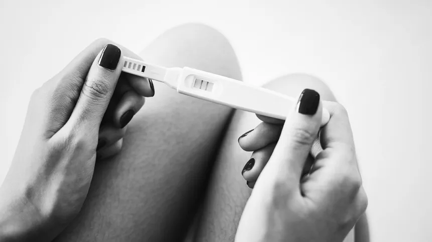 Frau hält positiven Schwangerschaftstest in den Händen