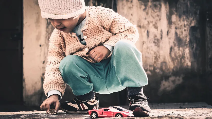 Kleines Mädchen spielt auf der Straße mit einem Auto
