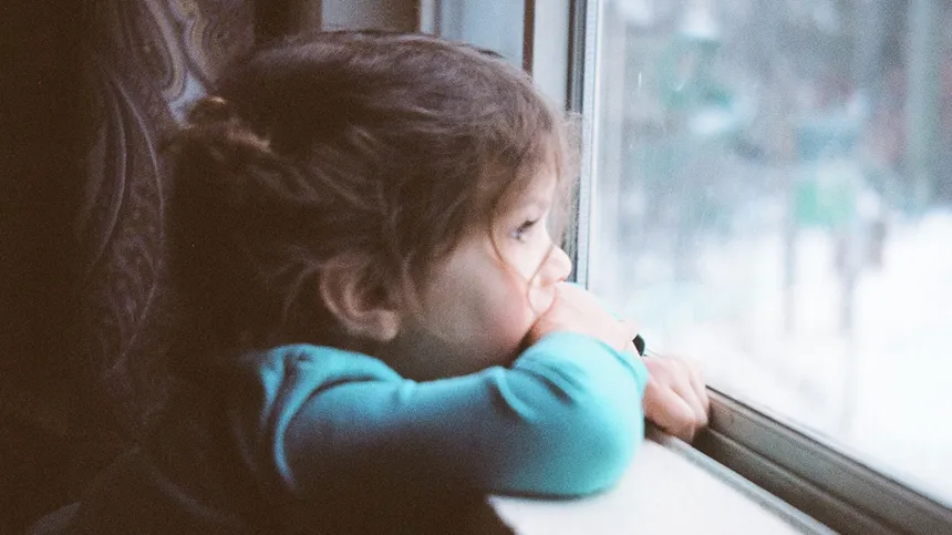 Kleines Mädchen ist krank und schaut aus dem Fenster