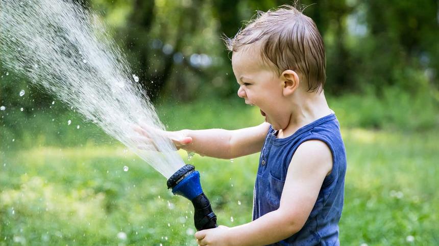 Junge spielt im Garten mit Wasser