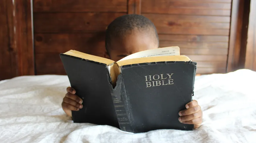 Kind im Bett mit einer Bibel