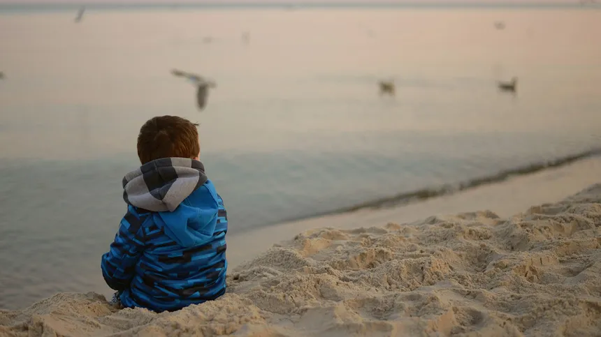 hochsensible Kinder - Kind sitzt alleine am Strand und Vögel fliegen