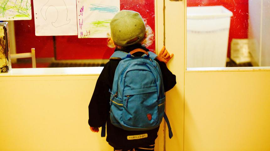Kindergarten-Kind steht vor einer Glastüre