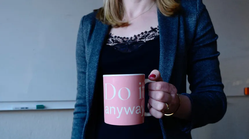 Junge Frau hält Kaffeetasse mit dem Schriftzug "do it anyway"
