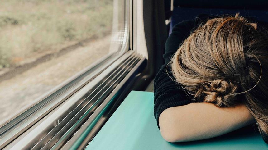 Frau sitzt müde im Zug